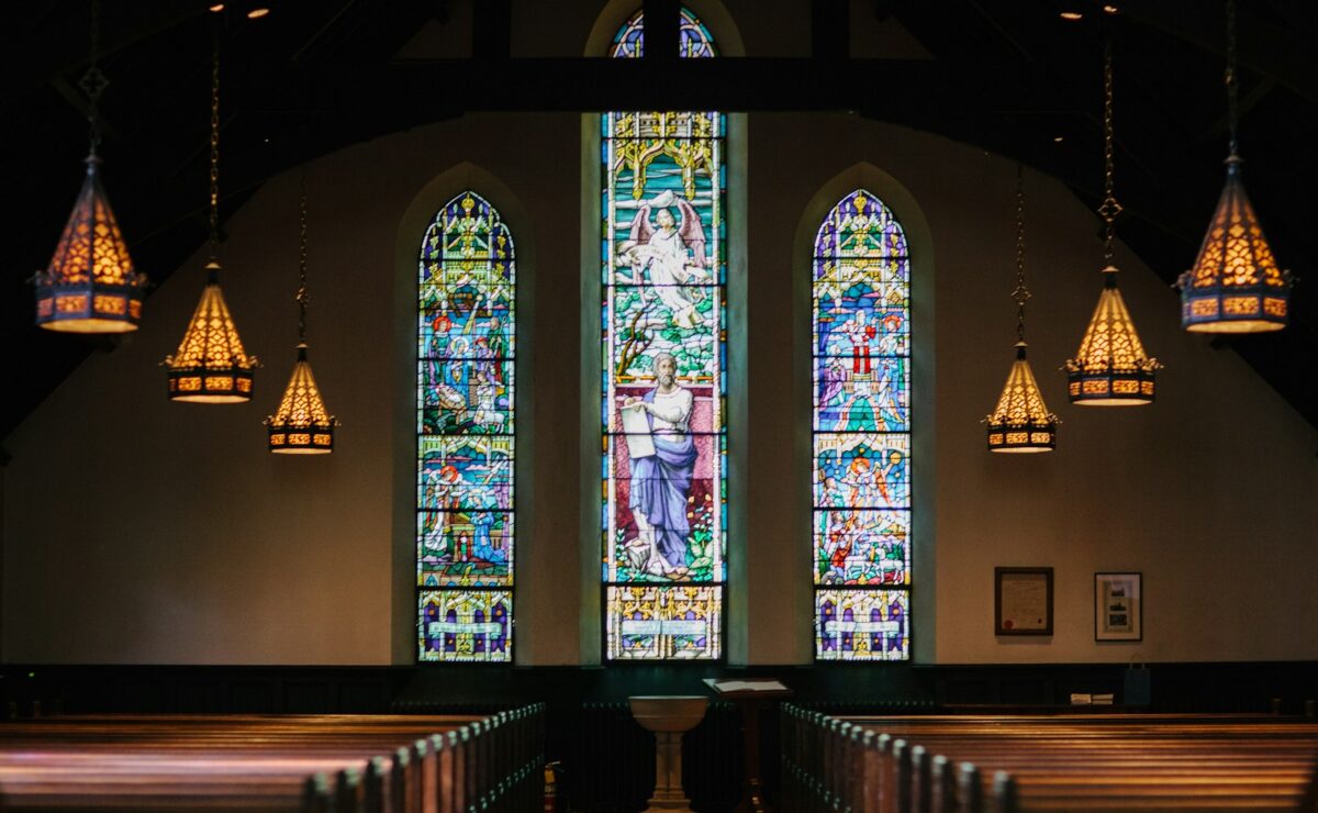 Stained-glass windows above rows of church pews