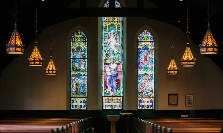 Stained-glass windows above rows of church pews